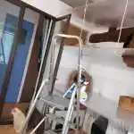 Les moments clés de l’aménagement de la chatterie | Montre l’intérieur de la pièce dédiée à mes chats. Au premier plan, on peut voir une échelle en aluminium que j’utilise pour nettoyer les trois plateaux transparents destinés à mes chats. En arrière-plan, l’un de mes chats, un Exotic Shorthair Colourpoint de couleur crème point, est visible. On peut également remarquer un spray ménager posé sur le plateau inférieur.