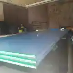 Les moments clés de l’aménagement de la chatterie | Présente plusieurs plaques de polycarbonate alvéolaire, empilées sur le toit de la voiture. Elle est stationnée à l’intérieur de notre garage encombré et désorganisé. Les murs du garage sont brut. Divers objets sont entreposés dans le garage. La lumière naturelle pénètre dans le garage par une ouverture non visible sur la photo.