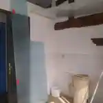 Les moments clés de l’aménagement de la chatterie | Illustre l’espace intérieur de la chatterie dédiée à mes chats, en rénovation. Des poutres sont apparentes sur le mur et des plaques épaisses de polycarbonate alvéolaire sont posées verticalement contre celui-ci. Des tasseaux de bois sont dispersés, ils serviront à soutenir les plaques alvéolaires. La scène est éclairée par une lumière naturelle provenant de la droite.